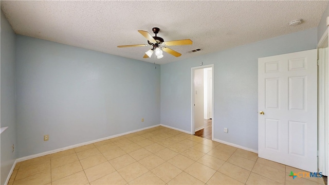 spare room featuring a textured ceiling, visible vents, a ceiling fan, and baseboards