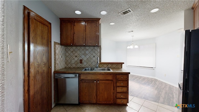kitchen featuring a sink, tasteful backsplash, freestanding refrigerator, a notable chandelier, and dishwasher