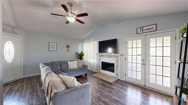 living area featuring lofted ceiling, wood finished floors, a textured ceiling, french doors, and a fireplace