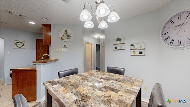 dining space with a textured ceiling, baseboards, visible vents, and a notable chandelier