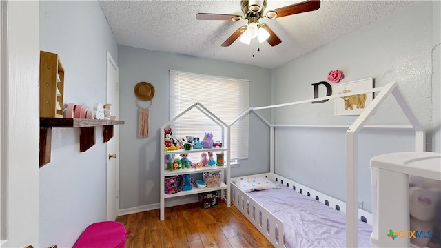 bedroom with hardwood / wood-style floors, a ceiling fan, baseboards, and a textured ceiling