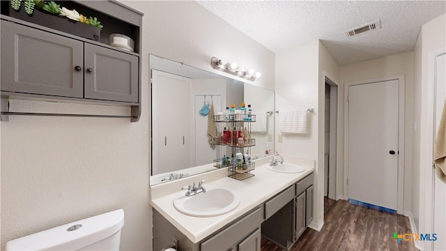 full bathroom with visible vents, a sink, a textured ceiling, and toilet