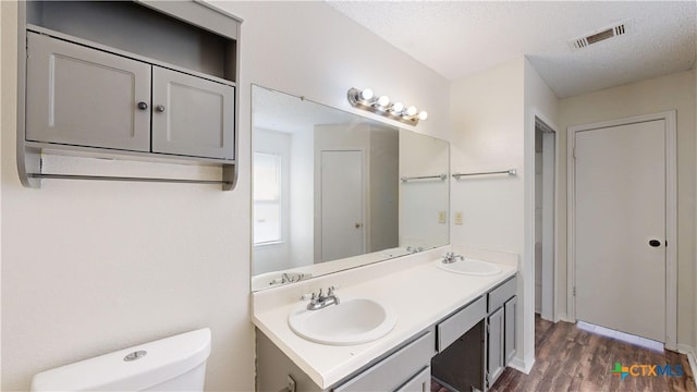 bathroom featuring wood finished floors, visible vents, toilet, and a sink