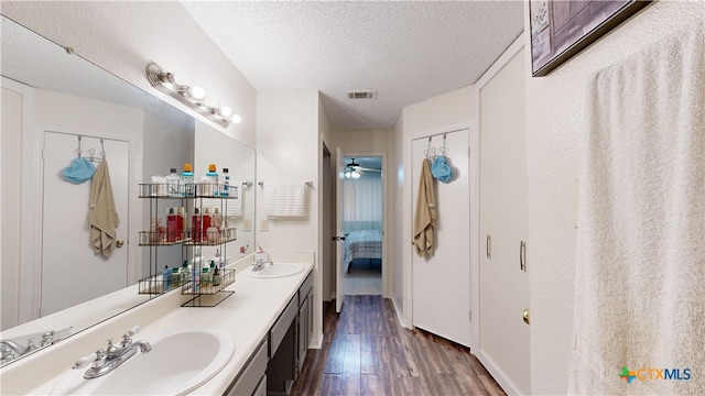 ensuite bathroom featuring wood finished floors, a sink, a textured ceiling, and ensuite bathroom