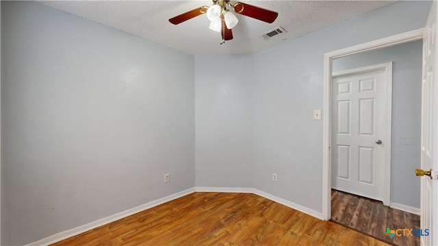 empty room with wood finished floors, a textured ceiling, ceiling fan, baseboards, and visible vents