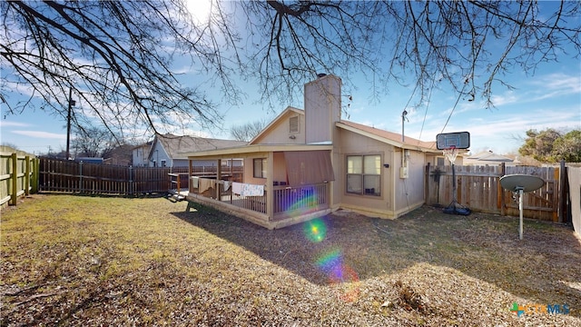 back of house featuring a fenced backyard, a lawn, and a chimney