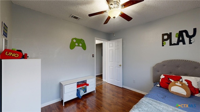 bedroom with a textured ceiling, wood finished floors, visible vents, and baseboards