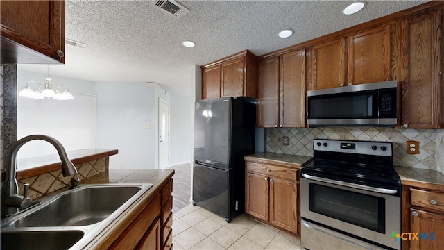 kitchen featuring stainless steel appliances, a sink, visible vents, a chandelier, and decorative backsplash