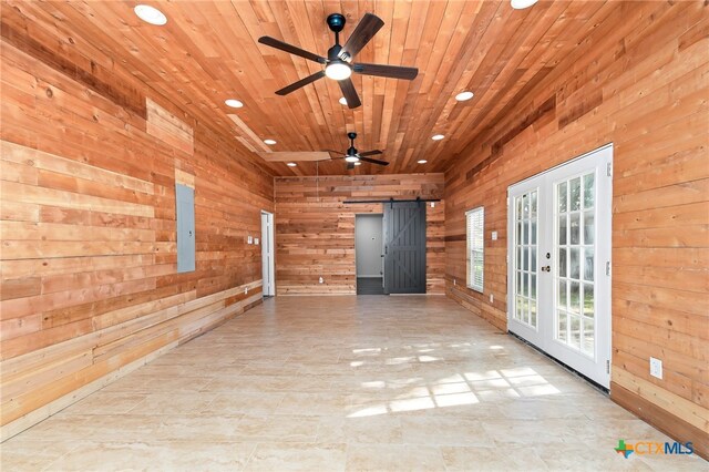 empty room with wooden walls, a barn door, and french doors