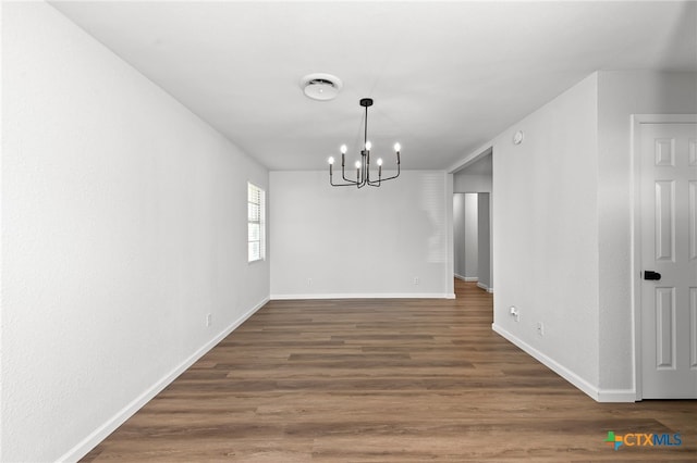 unfurnished dining area featuring dark wood-type flooring and a chandelier