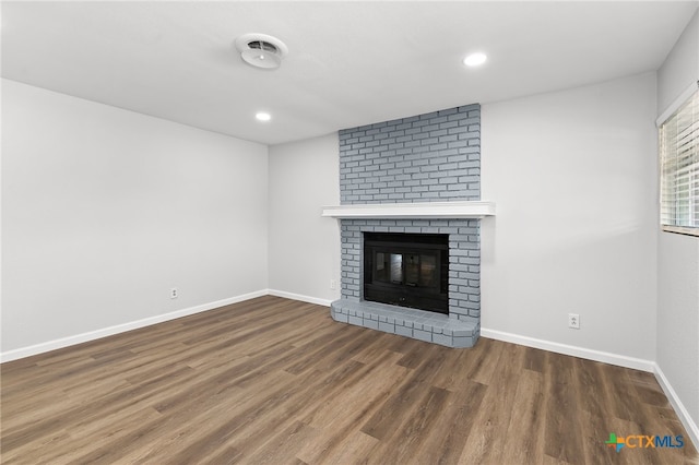 unfurnished living room with dark hardwood / wood-style floors and a brick fireplace