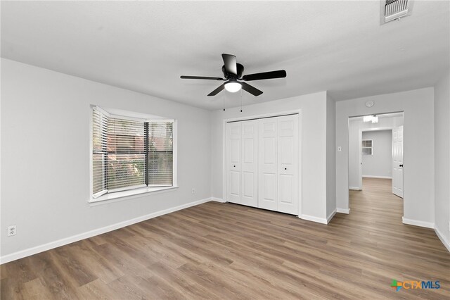 unfurnished bedroom with wood-type flooring, ceiling fan, and a closet