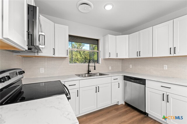 kitchen with dark wood-type flooring, white cabinets, decorative backsplash, sink, and appliances with stainless steel finishes