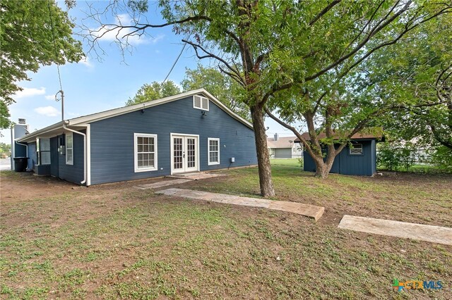 rear view of property with a yard, a storage shed, and french doors