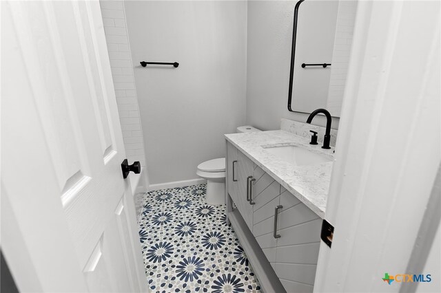 bathroom with toilet, vanity, and tile patterned floors