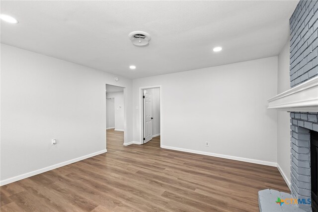 unfurnished living room with a fireplace and wood-type flooring