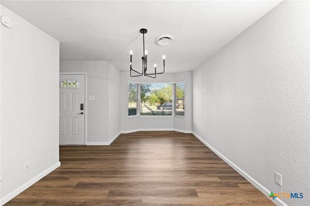 unfurnished dining area featuring dark wood-type flooring and a chandelier