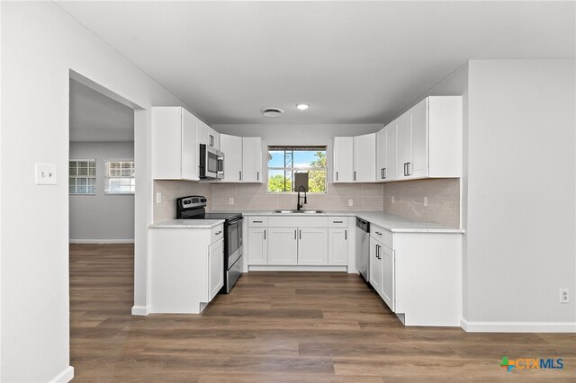 kitchen with dark hardwood / wood-style flooring, decorative backsplash, sink, white cabinetry, and appliances with stainless steel finishes