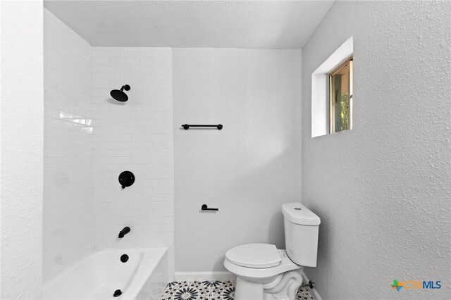 bathroom with a textured ceiling, toilet, and tiled shower / bath combo