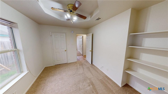 spare room with baseboards, a tray ceiling, visible vents, and carpet flooring