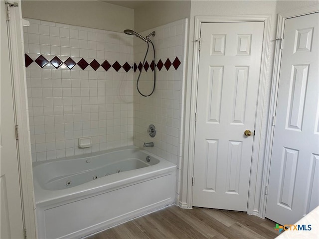 full bath with a combined bath / shower with jetted tub and wood finished floors