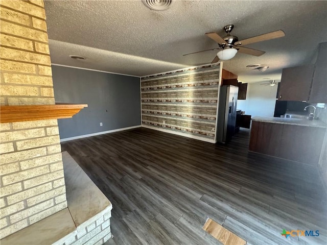 unfurnished living room with sink, ceiling fan, dark hardwood / wood-style floors, and a textured ceiling