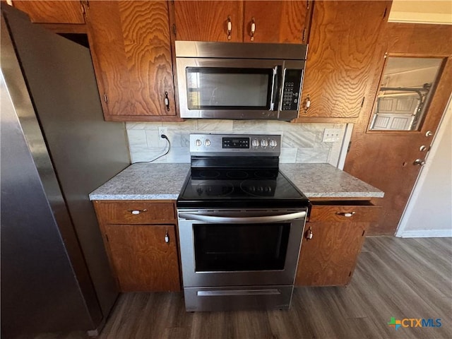 kitchen with dark hardwood / wood-style flooring, decorative backsplash, and stainless steel appliances