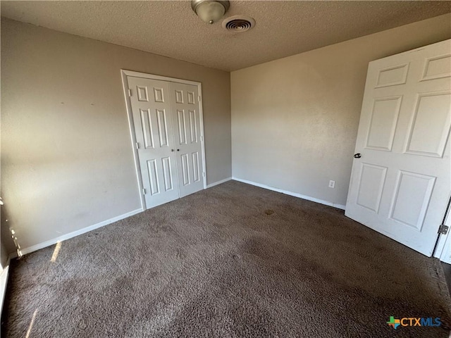 unfurnished bedroom featuring a textured ceiling, a closet, and dark carpet