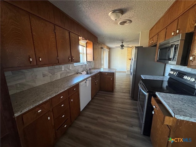 kitchen featuring a textured ceiling, appliances with stainless steel finishes, dark wood-type flooring, sink, and backsplash