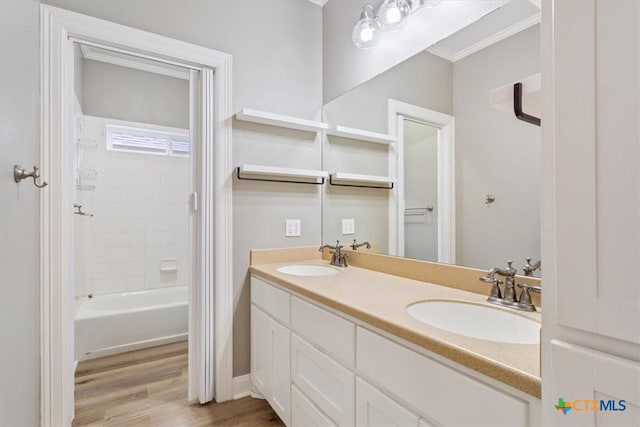 bathroom with double vanity, a sink, shower / bathtub combination, and wood finished floors