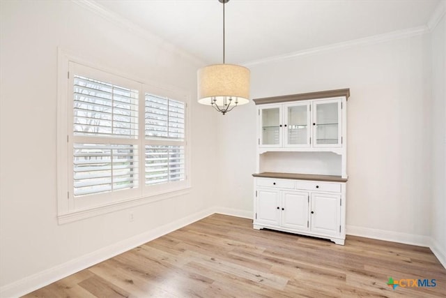 unfurnished dining area featuring baseboards, crown molding, a notable chandelier, and light wood finished floors