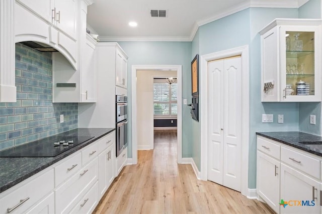 kitchen with black electric stovetop, visible vents, glass insert cabinets, white cabinets, and dark stone countertops