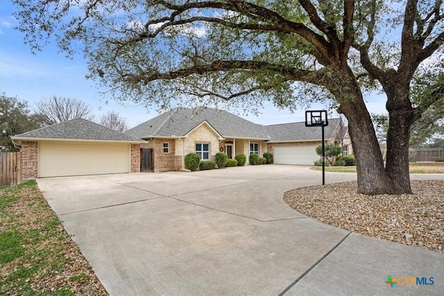 ranch-style home with a garage, brick siding, driveway, and fence