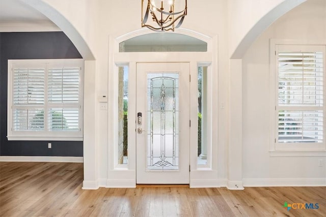 foyer entrance featuring light wood-style floors, a notable chandelier, and baseboards