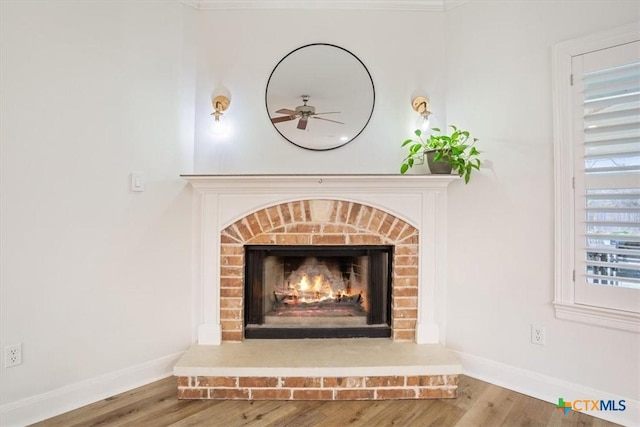 details with a fireplace, wood finished floors, a ceiling fan, and baseboards