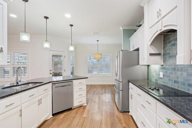 kitchen with stainless steel appliances, a sink, decorative light fixtures, and white cabinetry