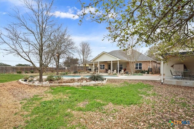 rear view of house with a fenced in pool, a patio area, fence, and a lawn