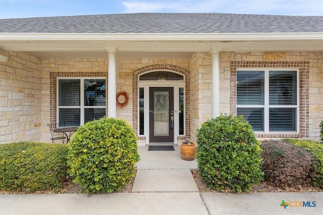 property entrance with brick siding and roof with shingles