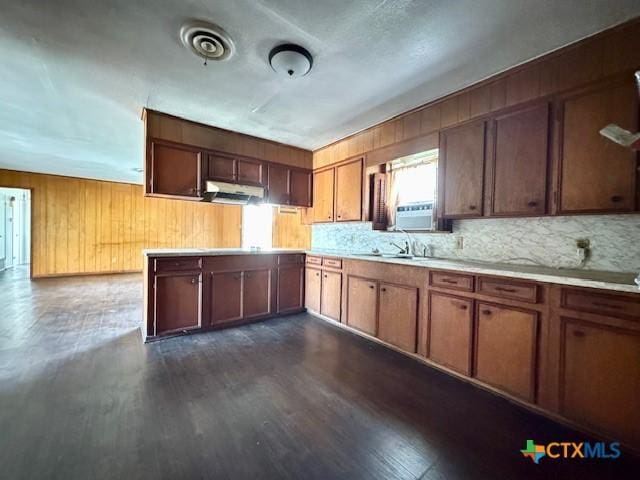 2009 S Laurent St, Victoria, TX 77901 - kitchen featuring under cabinet range hood, light countertops, dark wood-style floors, backsplash, and wood walls