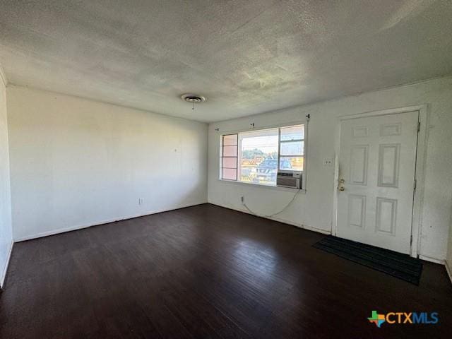 2009 S Laurent St, Victoria, TX 77901 - unfurnished room featuring a textured ceiling, dark wood-style floors, and cooling unit