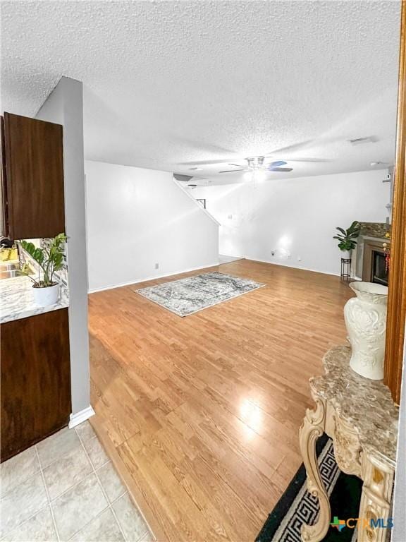 unfurnished living room featuring light wood-type flooring, a fireplace, and a textured ceiling