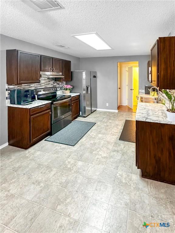 kitchen featuring visible vents, appliances with stainless steel finishes, light countertops, under cabinet range hood, and a sink