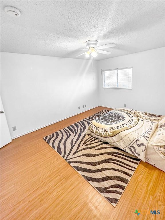 interior space featuring a textured ceiling, a ceiling fan, and wood finished floors
