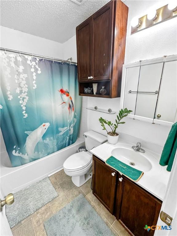 full bathroom with a textured ceiling, toilet, vanity, tile patterned floors, and shower / tub combo with curtain