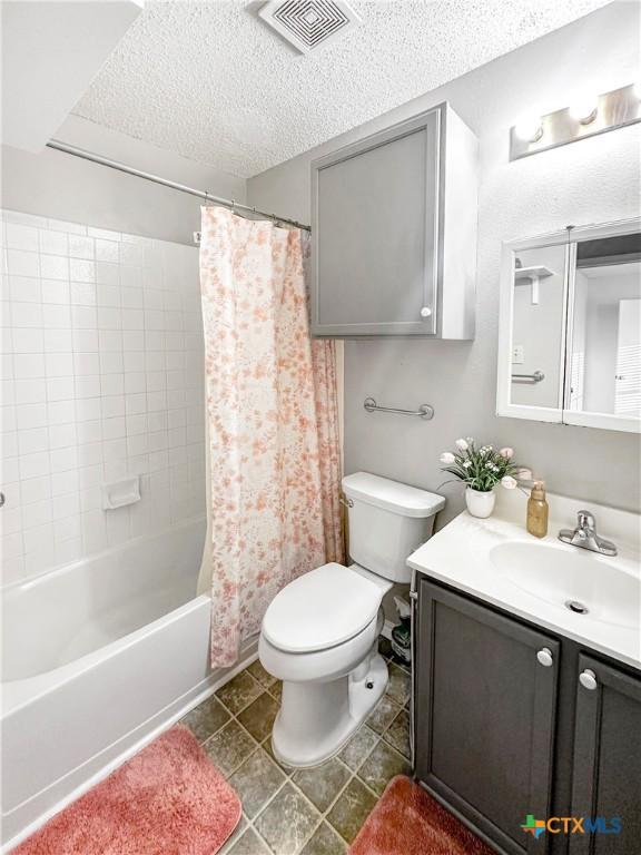 full bathroom featuring visible vents, toilet, vanity, shower / bath combination with curtain, and a textured ceiling