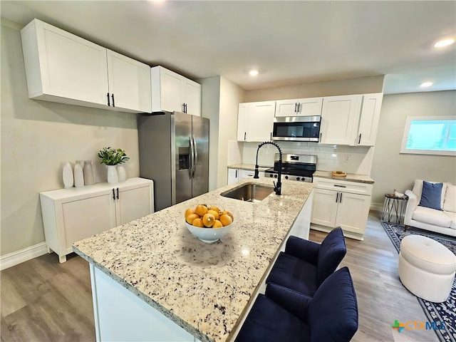 958 E Humphreys St, Seguin, TX 78155 - kitchen with stainless steel appliances, a sink, light stone counters, baseboards, and light wood finished floors
