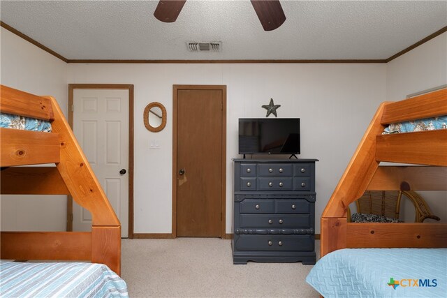 carpeted bedroom featuring ceiling fan, a textured ceiling, and crown molding