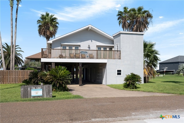 raised beach house with a front lawn, a deck, and a carport