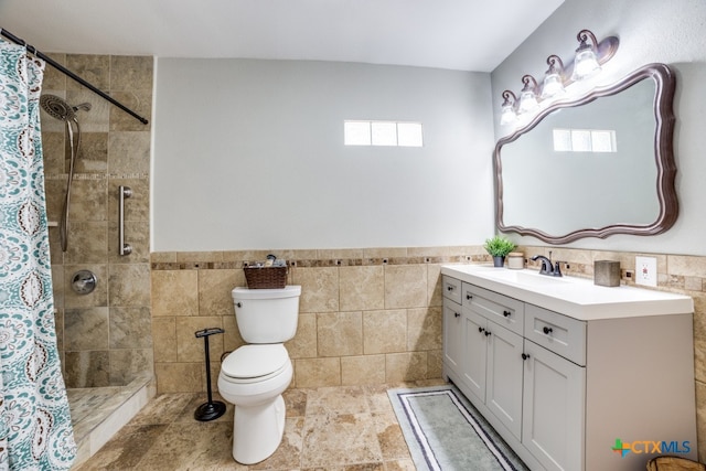 bathroom with tile walls, vanity, toilet, and a shower with curtain