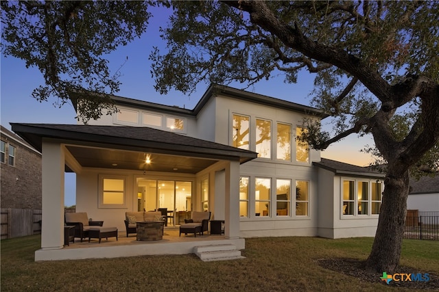 back house at dusk featuring outdoor lounge area, a yard, and a patio